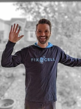 man wearing a shirt with a FixNcell logo at the door of a customer's house enthusiastically ready to fix a phone